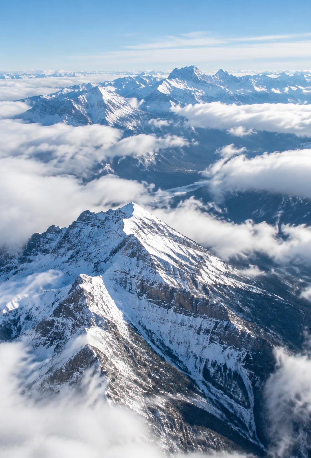 Snow-covered Canadian Rocky Mountain peaks rising above the clouds